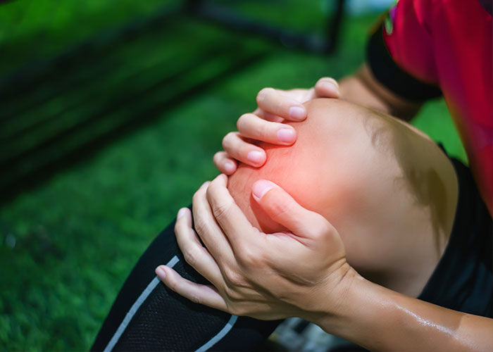 Fußballspielerin hält sich das Knie - Bild vor der Anwendung einer Knorpeltherapie bei Dr. Lang
