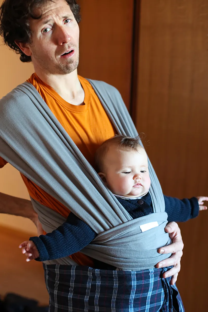 Mann mit Baby auf den Bauch gebunden