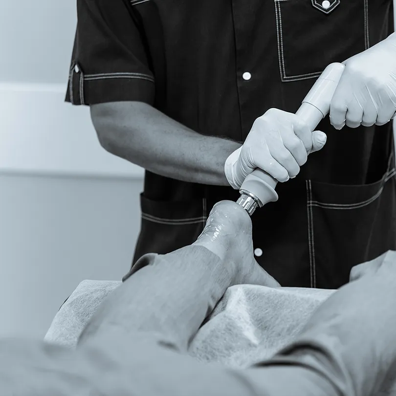 Frau wird mit Stoßwellen am Fuß behandelt