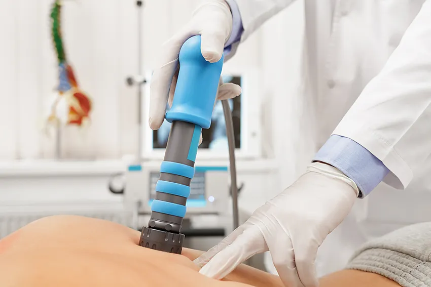 Frau wird mit Stoßwellen am Rücken behandelt