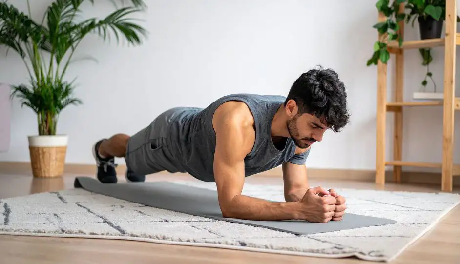 Mann führt Planke auf Yogamatte durch, Rumpfkräftigung zur Vorbereitung auf die Wandersaison